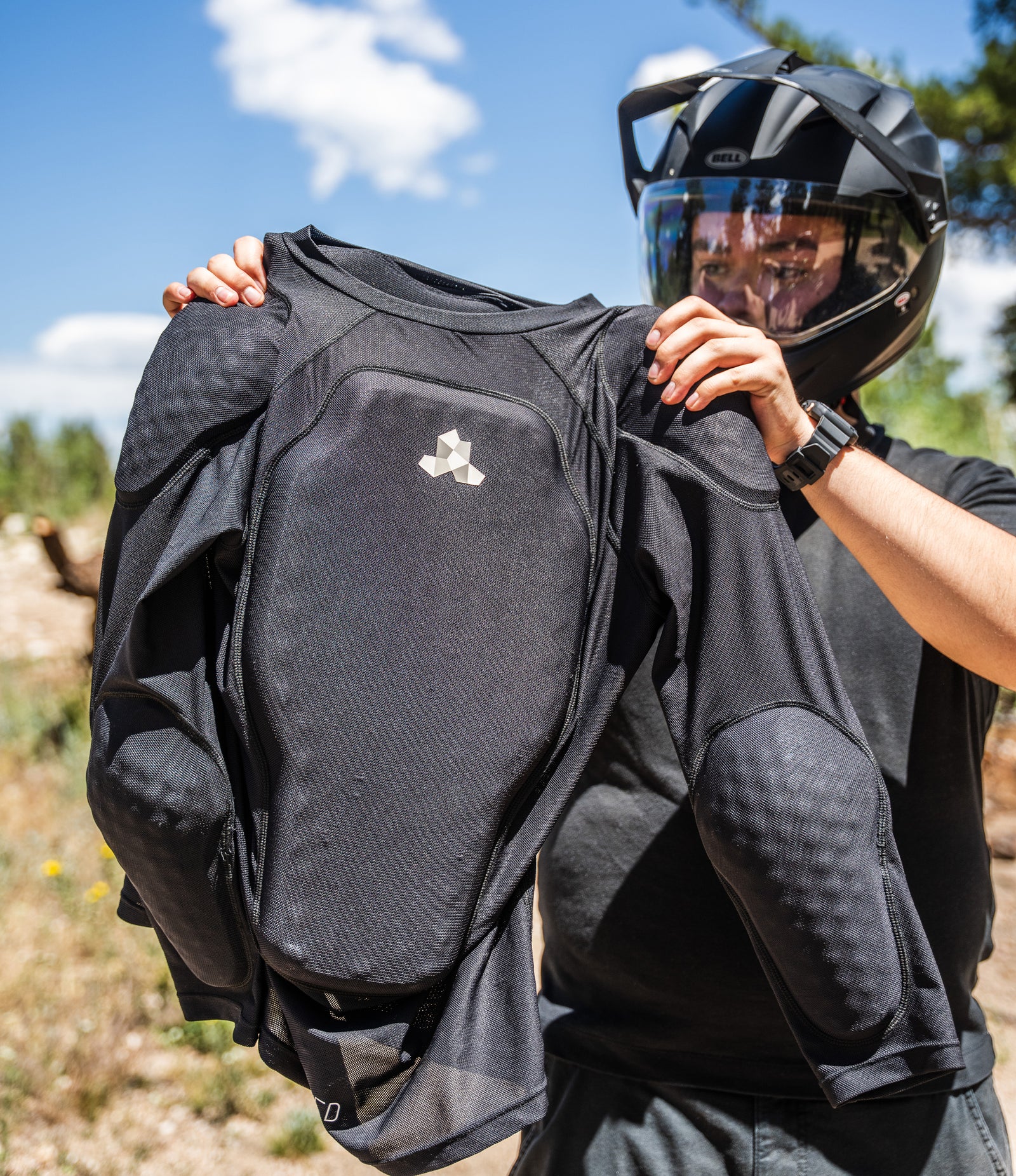 Rider holding up a Cased long-sleeve inner protective riding jersey showing chest, shoulder, and elbow padding.