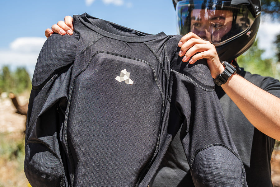 Rider holding up a Cased long-sleeve inner protective riding jersey showing chest, shoulder, and elbow padding.